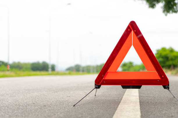 triangle de panne se tient aux côtés de la route.
voiture est tombé en panne le signe sur la notion de la route. - bord de route photos et images de collection