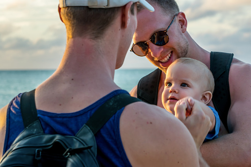 Homosexual godparents and their godchild by the beach of Varadero at sunset, Cuba.