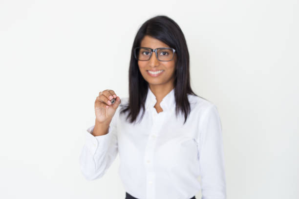 Smiling beautiful female couch holding presentation. Young Indian woman writing on glass board. Teaching or training concept