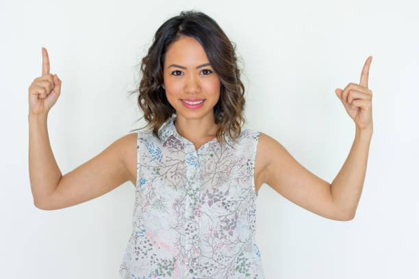 istock Smiling young woman pointing upwards with both forefingers 1095734526