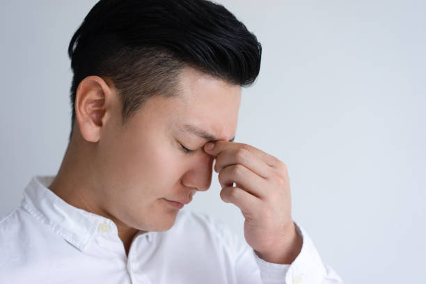 istock Tired young Asian man touching his nose bridge 1095737722
