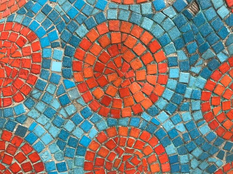 orange pieces of square mosaic created as beautiful circle pattern and blue color as background