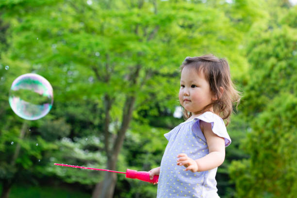 istock Toddler girl playing with soap bubbles 1095782674