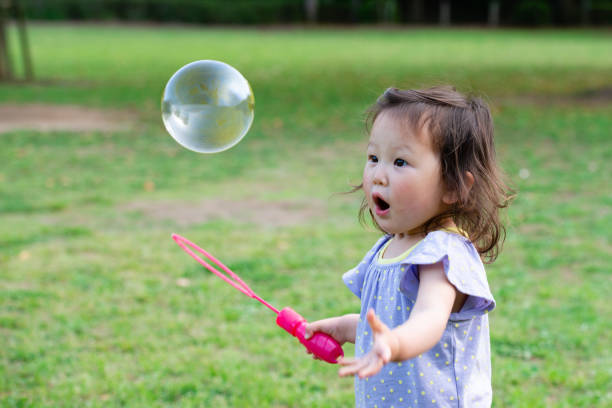 toddler girl playing with soap bubbles - japanese girl imagens e fotografias de stock