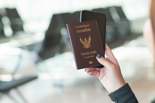Travel concept. Closeup of woman hand holding Thai passport ready to boarding.