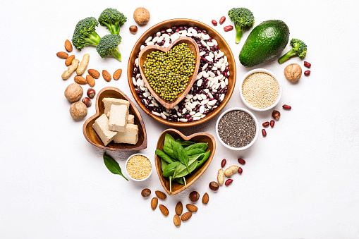 Sources of vegetable protein laid out in the shape of a heart on a white background.