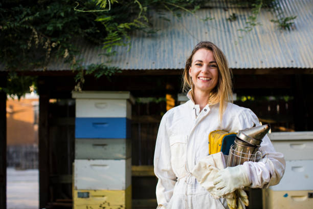 Beekeeper in front of her bee hives Beekeeper in front of her bee hives beekeeper photos stock pictures, royalty-free photos & images