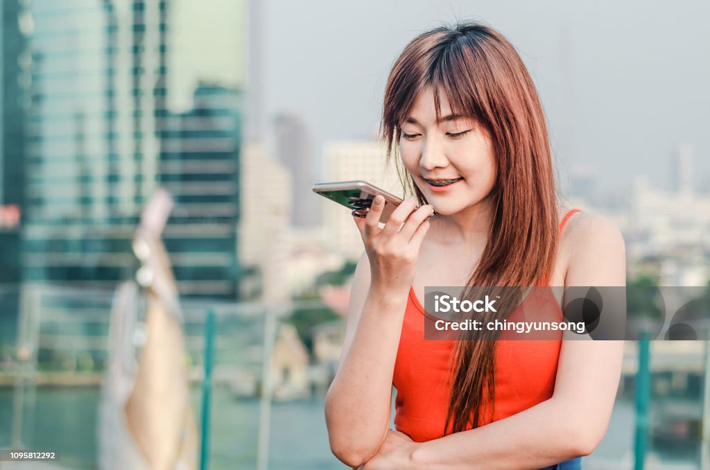 Happy confident woman talking on the mobile cell phone on speakerphone over city background Applying Stock Photo