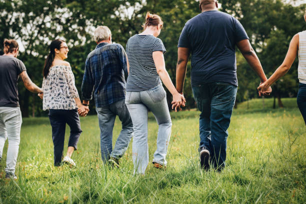 divers peuples tenant par la main et en cours d’exécution dans le parc - holding hands human hand holding multi ethnic group photos et images de collection