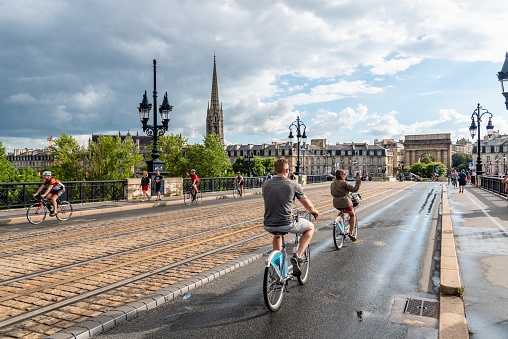 Bordeaux, France - July 22, 2018: Scenic view of Pont de Pierre Bridge with cyclists a rainy day of summer