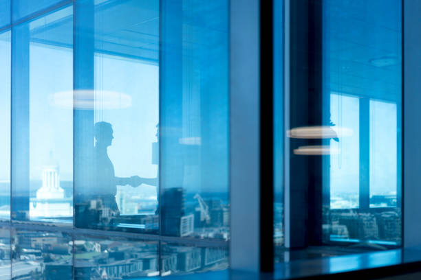istock Male colleagues shaking hands seen through glass 1095832458