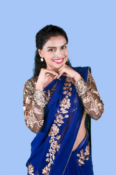 Portrait of young Indian woman looks awkward while wearing a blue saree clothes in the studio
