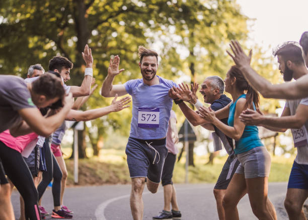 フィニッシュ ラインでの選手の陽気なマラソン ランナー挨拶グループ。 - marathon running group of people jogging ストックフォトと画像