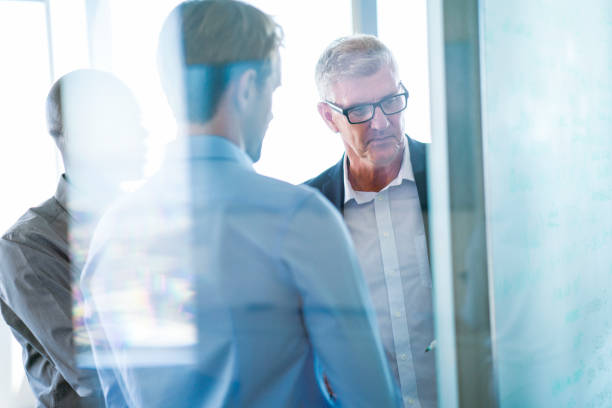 istock Businessmen discussing over whiteboard in office 1095845584