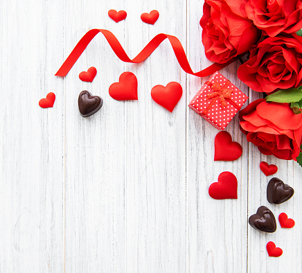 Valentines day romantic background -  gift box, candy and roses  on a wooden  background