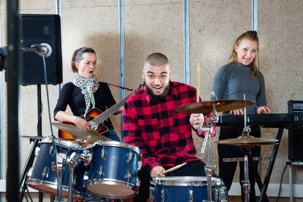 istock Expressive drummer with his bandmates practicing in rehearsal room 1095862974