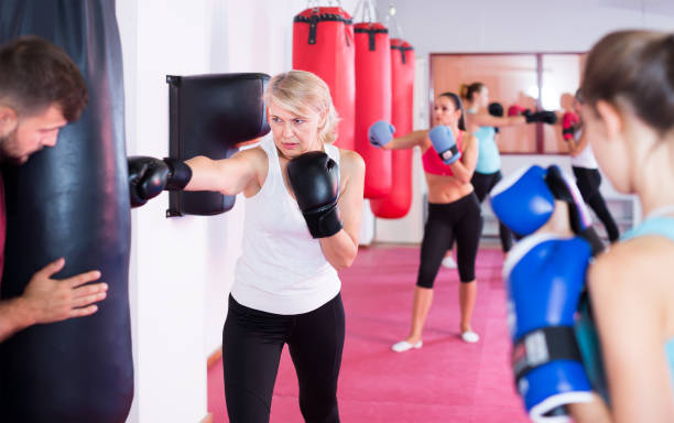 istock active mature female is doing exercises with punching bag in gym 1095863404
