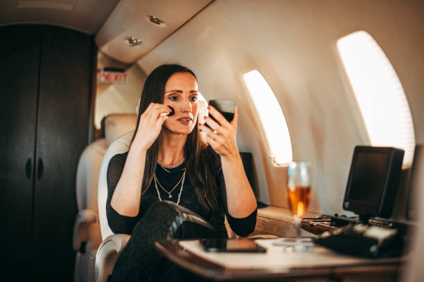 istock Successful woman touching up her make-up using a pocket mirror while traveling on a private jet 1095866674