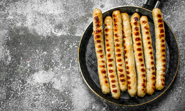 istock Fried sausages with spices in a frying pan. 1095867428