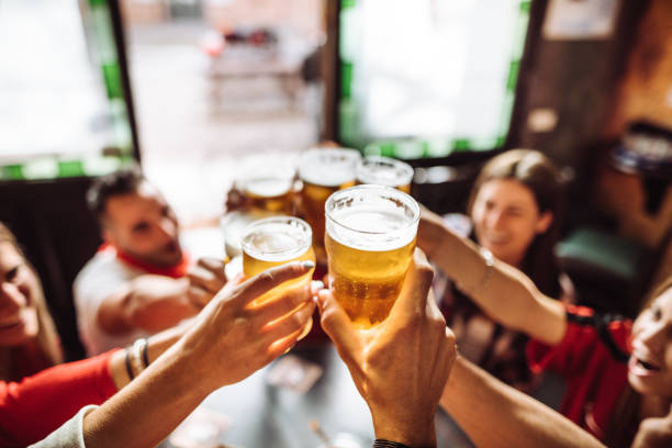 people talking and toasting in a pub with the beers people talking toasting in a pub with the beers oktoberfest beer stock pictures, royalty-free photos & images