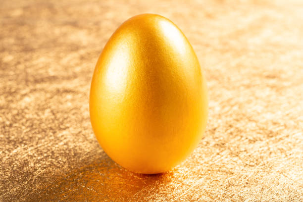 istock gold egg stands on a golden background 1095888562