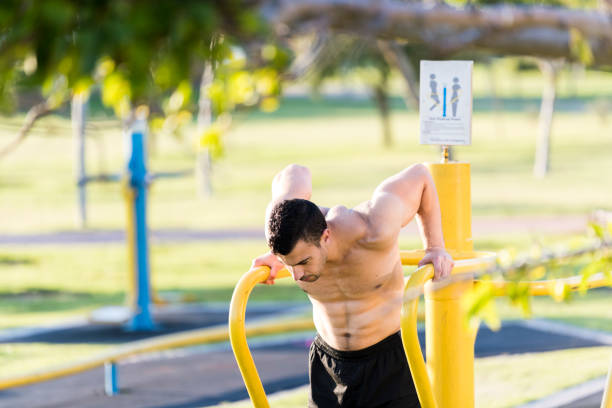 Close up young man exercising using a dipping station