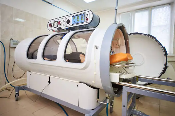Photo of a girl in a black T-shirt lies in a hyperbaric chamber, oxygen therapy