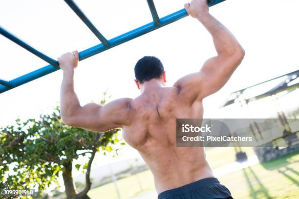 Muscle Up Back Of Young Man Doing Muscleups In Public Park Stock Photo - Download Image Now