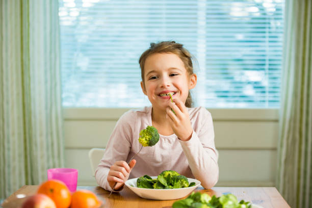 istock Cute girl eating spinach and broccoli at the table 1095904200