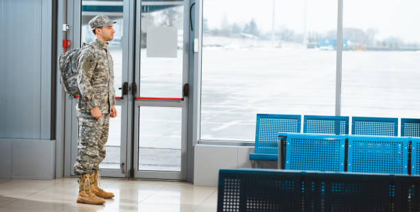 istock veteran in military uniform standing with backpack in departure lounge 1095937350