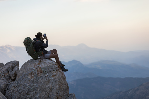 Man sitting at the edge of a cliff using phone.