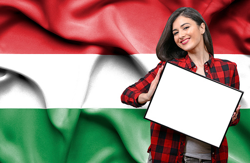 Woman holding blank board against national flag of Hungary
