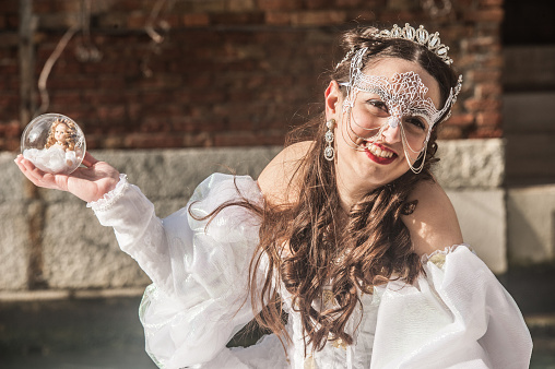Beautiful Woman at Venice Carnival Posing in White Carnival Costume Holding Sphere with Doll Inside