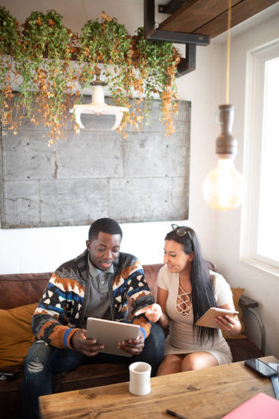 istock Mixed race couple in cafe having fun with their tech devices 1095967132