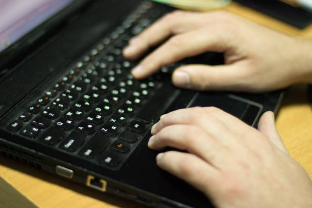 istock The hands of the programmer, he working on a laptop with a Russian keyboard. The frame is in a selective focus. 1095973638