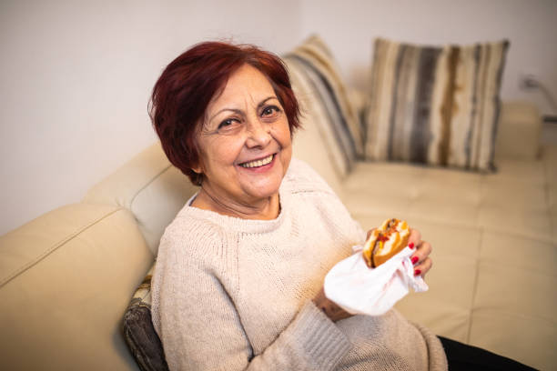 istock Cheerful senior woman eating hamburger 1095973772