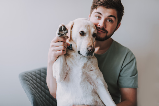 Young bearded man holding the palm of his dog while resting together