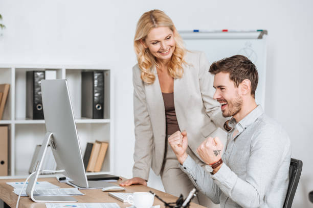 istock smiling female mentor looking at happy young businessman working with desktop computer in office 1095985394