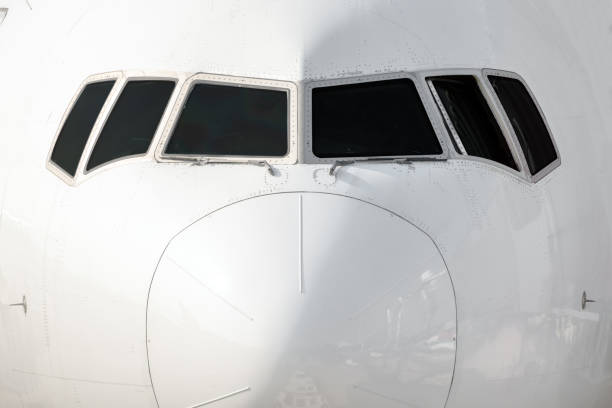 Close front outside view of a white big jet plane cockpit.