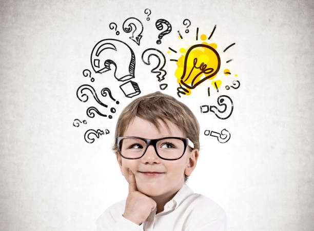 istock Little boy in glasses question marks and lightbulb 1095991730