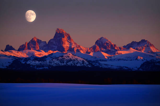 Sunset light with alpen glow on Tetons Tetons mountains rugged with moon rising