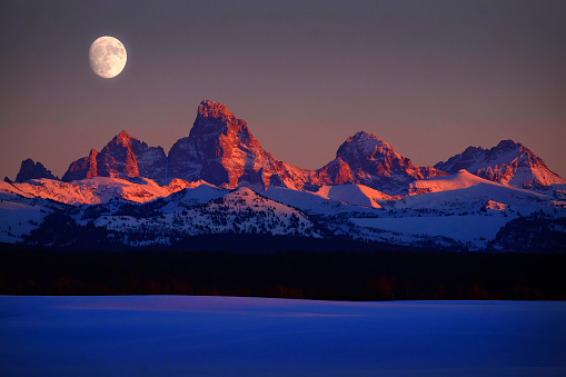 Sunset light with alpen glow on Tetons Tetons mountains rugged with moon rising