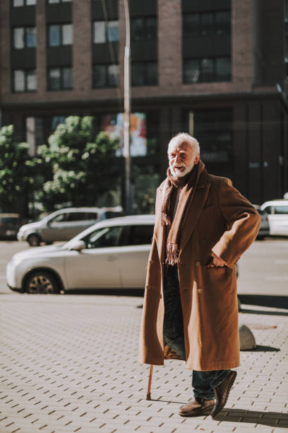 istock Stylish old man with cane looking away and smiling 1096001886