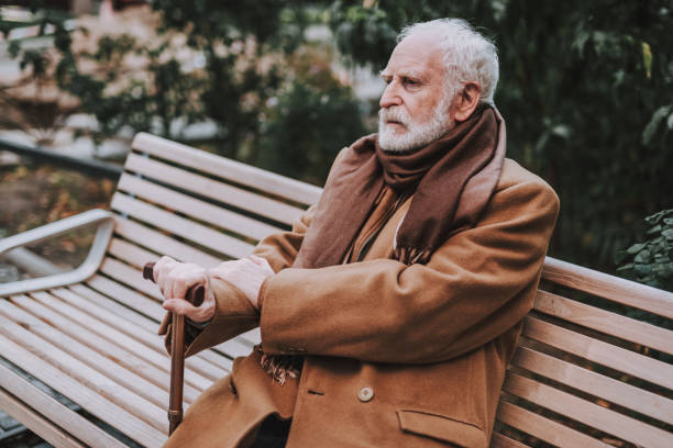 istock Stylish old man in coat sitting on bench 1096001944