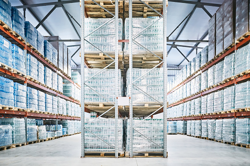 Hangar warehouse with rows of shelves with transparent plastic bags with ready-made factory production of bottled mineral water.