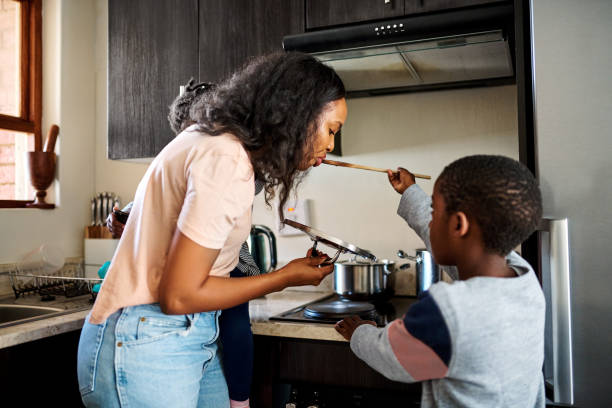 Mommy gets the first taste Shot of a little boy giving his mother a taste of the food he's preparing at home family dinners and cooking stock pictures, royalty-free photos & images