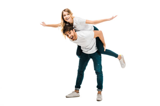 istock cheerful young couple piggybacking and smiling at camera isolated on white 1096019310