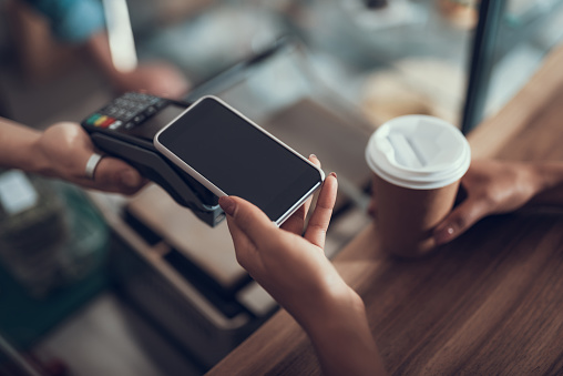 Mano de joven colocando smartphone en máquina de pago de tarjeta de crédito photo