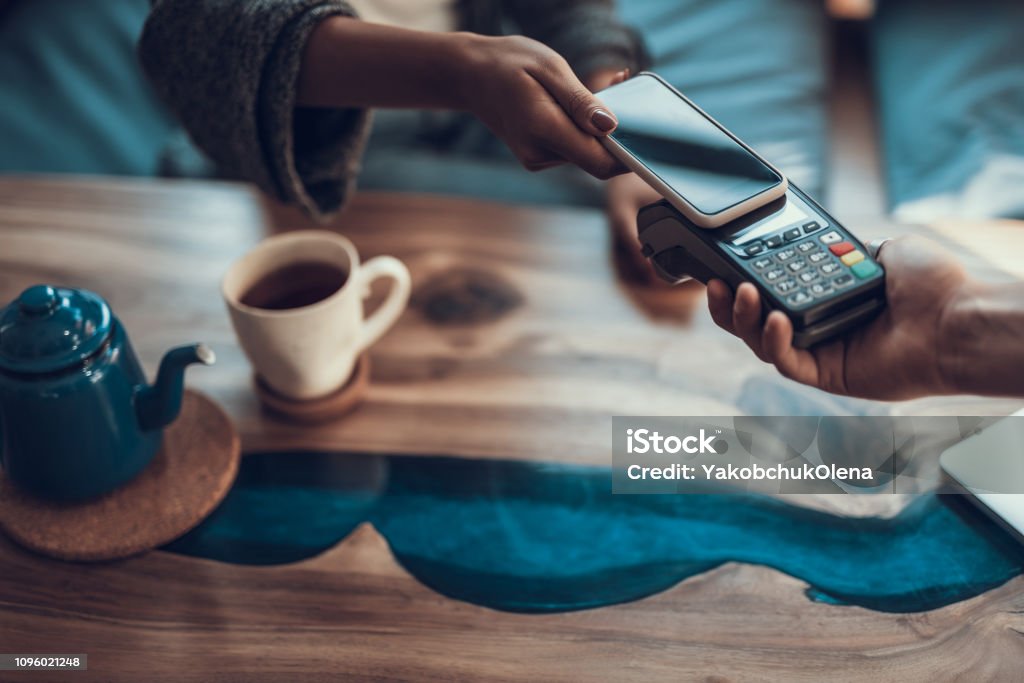 Horizontal image of contactless payment with smartphone Close up of woman hand with manicure putting her smartphone to the credit card payment machine while using contactless system of payment in the cafe Mobile Payment Stock Photo