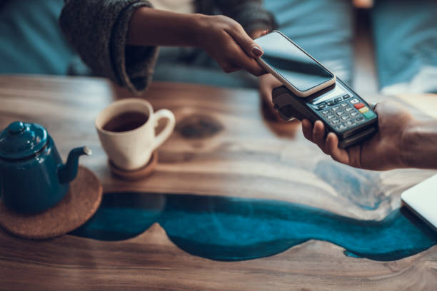 Horizontal image of contactless payment with smartphone Close up of woman hand with manicure putting her smartphone to the credit card payment machine while using contactless system of payment in the cafe mobile payment photos stock pictures, royalty-free photos & images